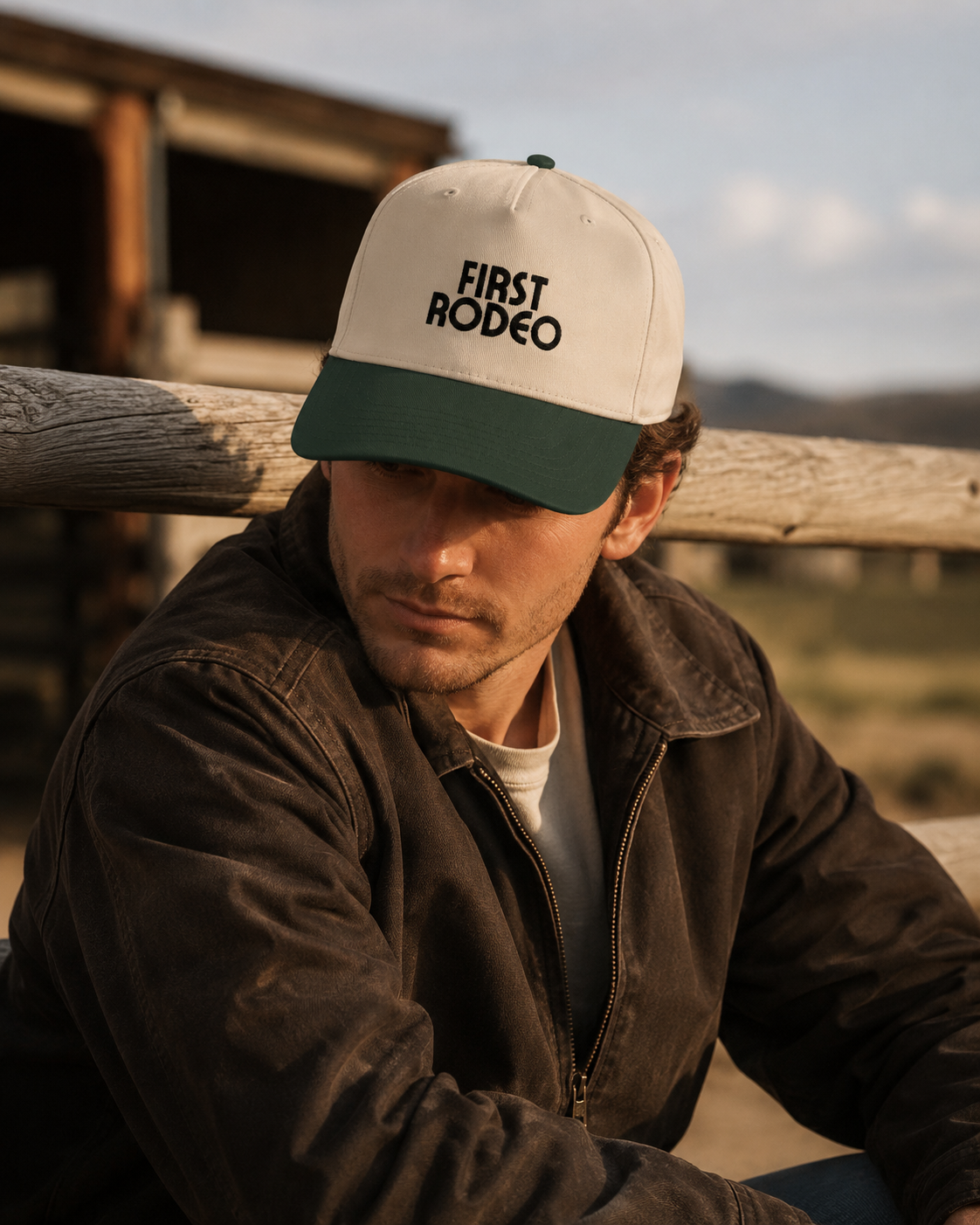 First Rodeo embroidered western snapback hat in cream and dark green displayed on a rustic wooden table with western decor background.